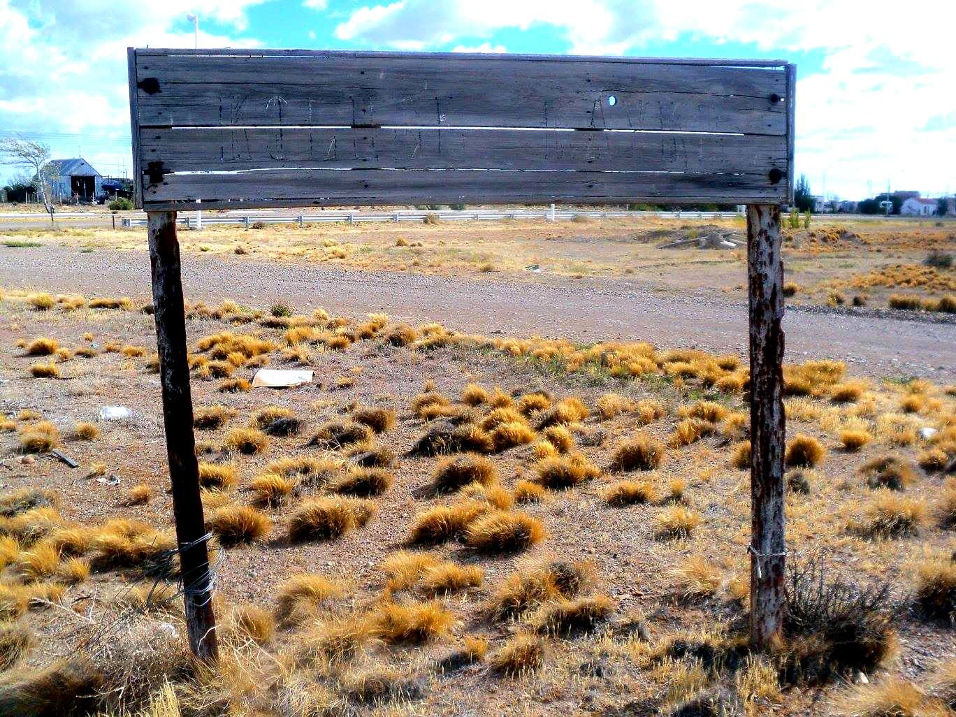 Cartel de la ex estación de Koluel Kayke con el pueblo detrás
